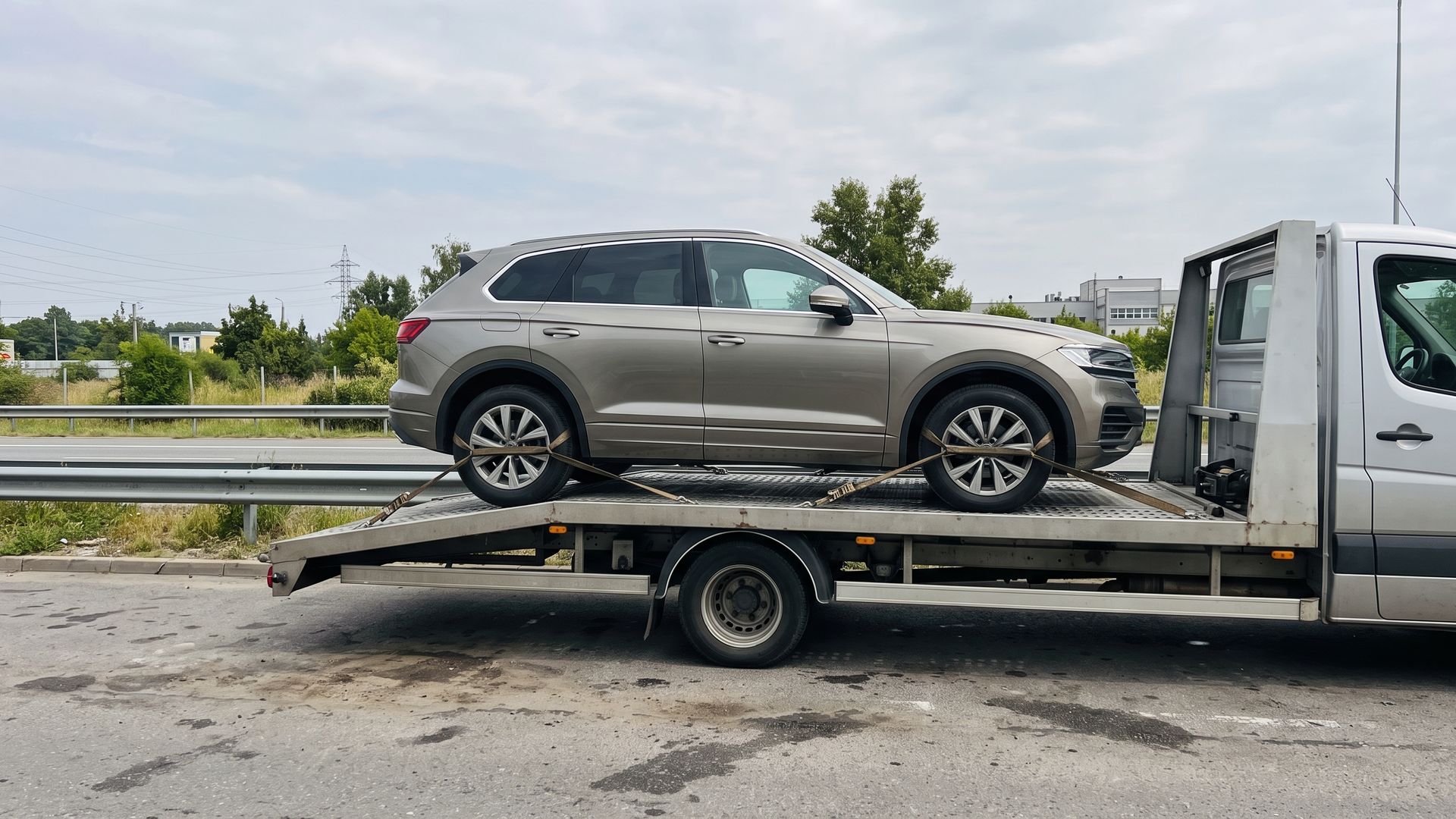 A car secured on an open carrier truck, photographed from the side with no number plate readable