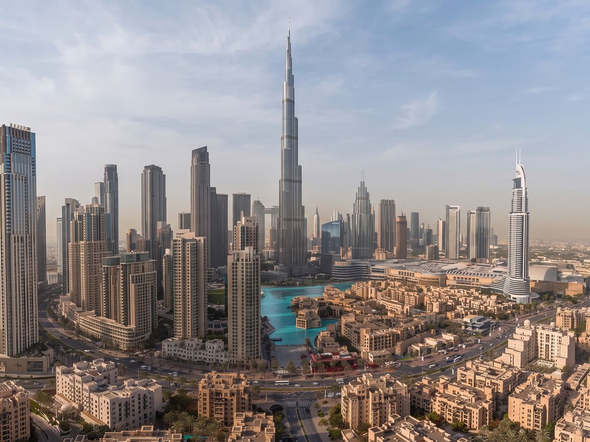 Sealed cartons on a bright logistics apron with desert haze and modern glass towers soft far away